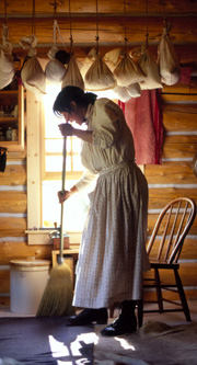 Woman sweeping log cabin's floor