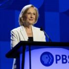 Paula Kerger, PBS President, stands at a podium wearing a white blazer at the 2024 PBS Annual Meeting in Las Vegas.