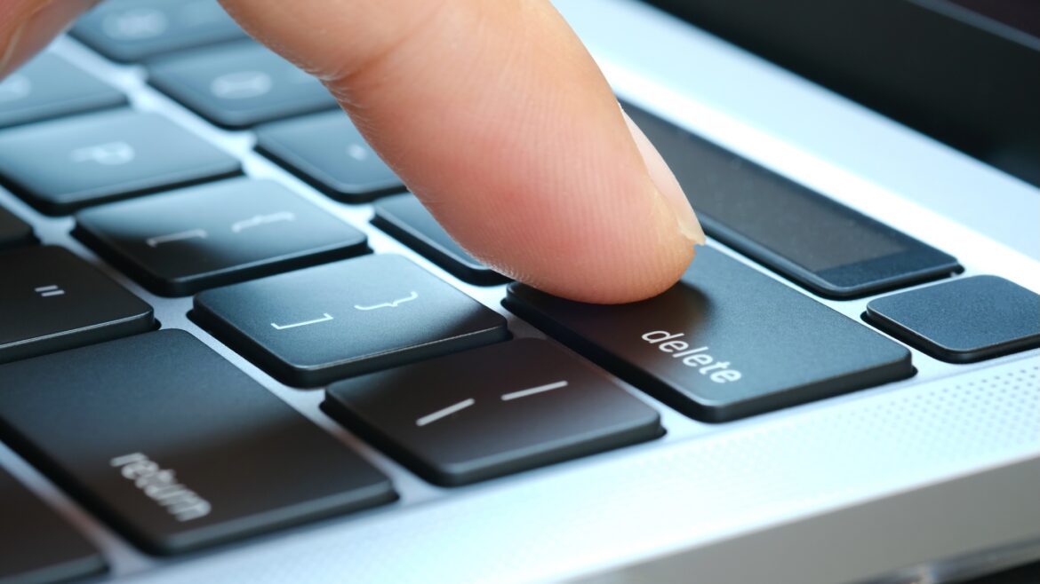 A finger pressing a delete key on a computer keyboard