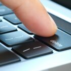 A finger pressing a delete key on a computer keyboard