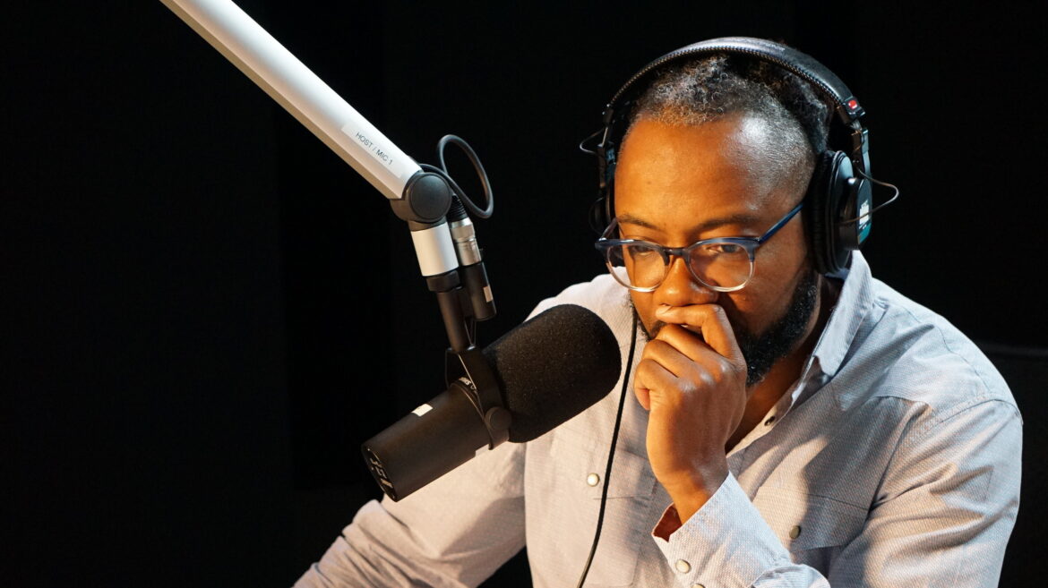 Al Letson sits at a microphone as he records in the Reveal studio.