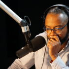 Al Letson sits at a microphone as he records in the Reveal studio.