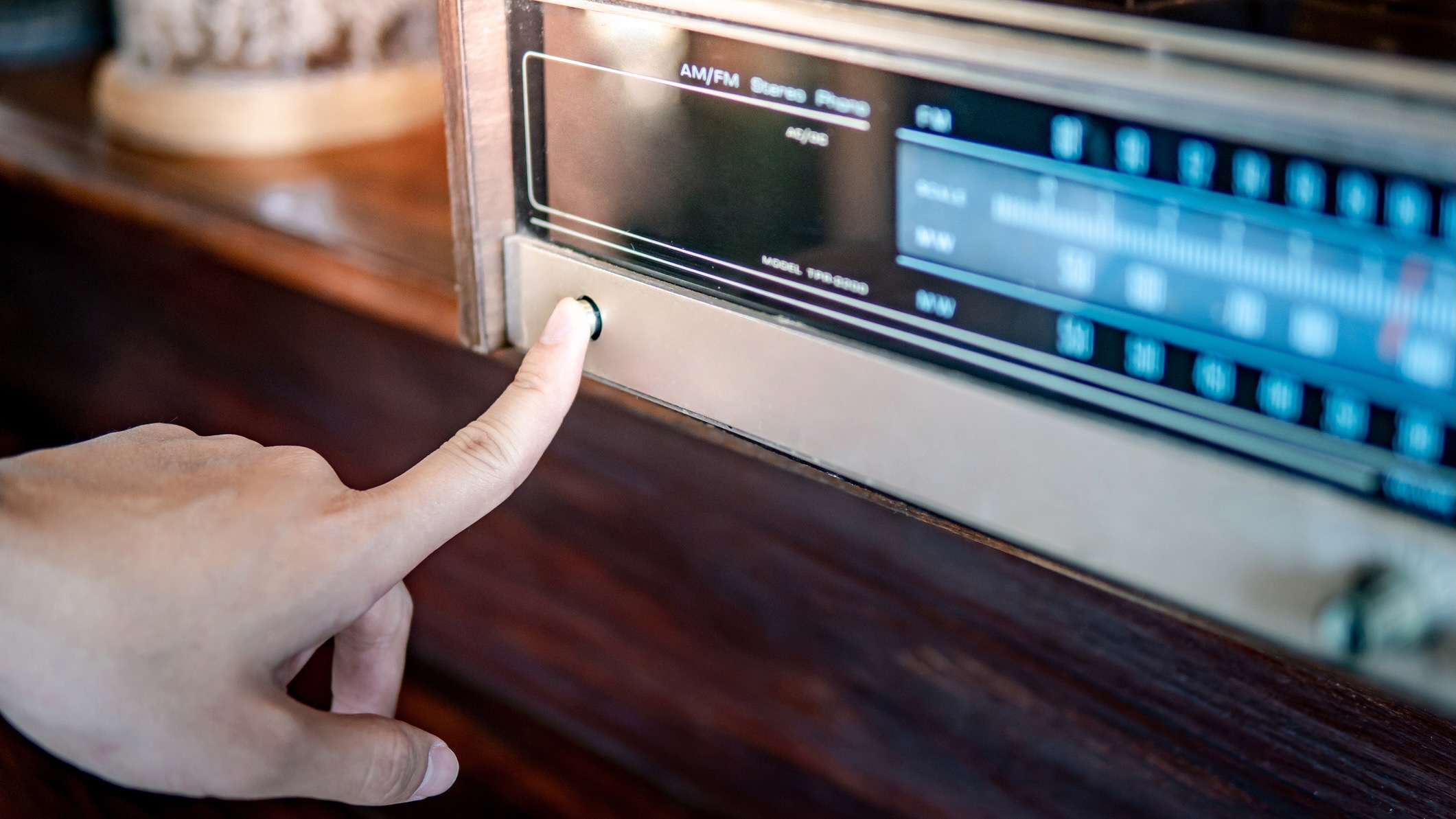 Male hand turning on retro radio by pressing power button.
