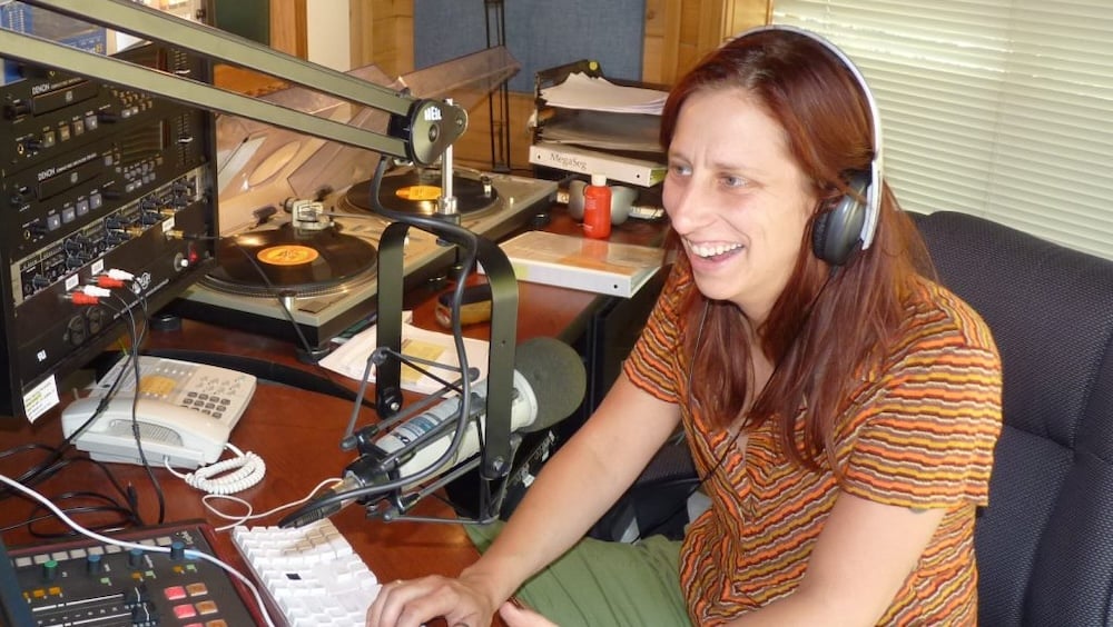 Woman with headphones on in typing on keyboard in radio studio.