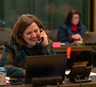 Morgan Watkins, an LPM reporter, talks on the phone, smiling, during a fundraiser