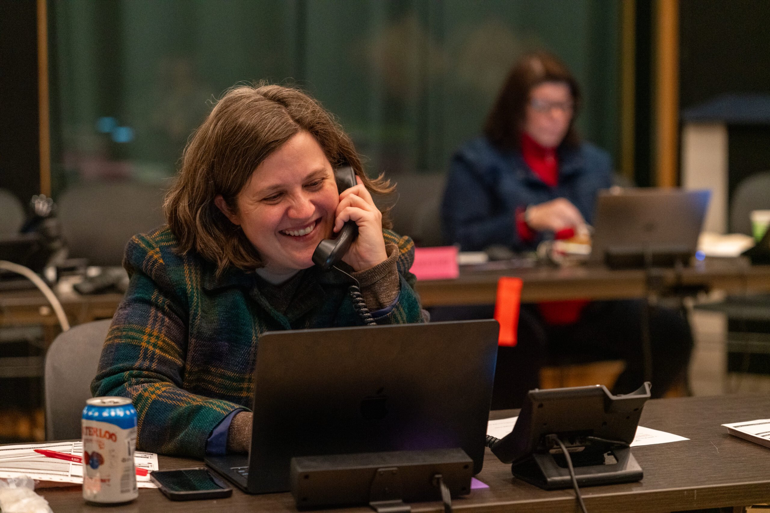 Morgan Watkins, an LPM reporter, talks on the phone, smiling, during a fundraiser