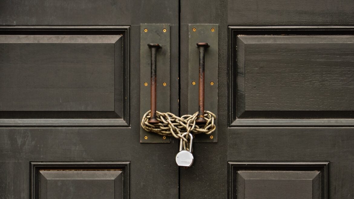 A wooden door padlocked with a chain
