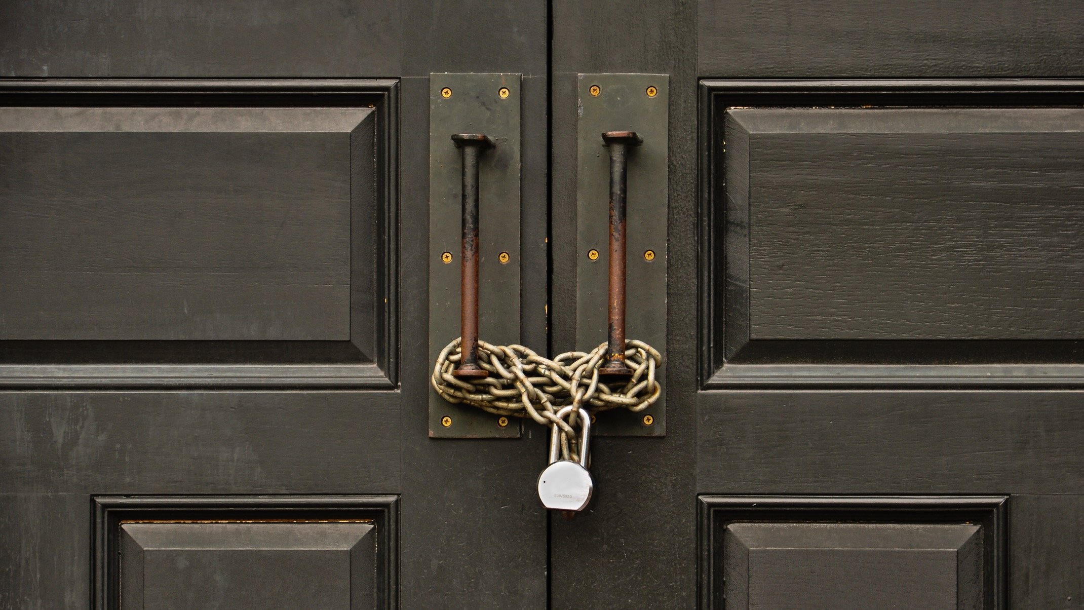 A wooden door padlocked with a chain