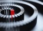 A conceptual image of a red domino at the center of a whirlpool-patterned chain of black dominos.