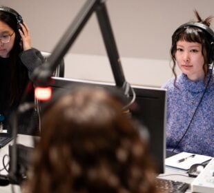 KQED TVC producers Jennifer Ng, left, and Emiko Oda interview reporter Erin Baldassari in a recording studio.