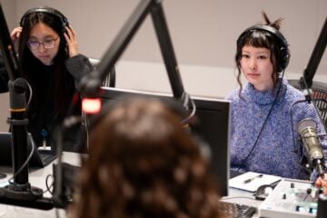 KQED TVC producers Jennifer Ng, left, and Emiko Oda interview reporter Erin Baldassari in a recording studio.