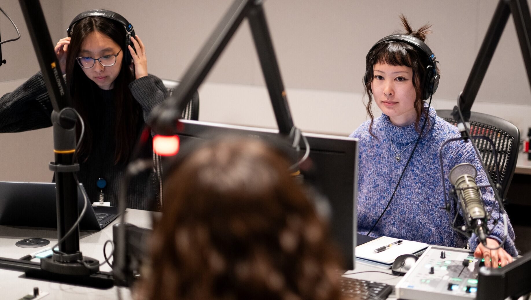 KQED TVC producers Jennifer Ng, left, and Emiko Oda interview reporter Erin Baldassari in a recording studio.