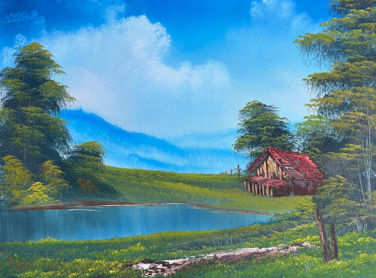 Bob Ross' paintiing "Home in the Valley." A serene landscape with a small wooden cabin with a red roof beside a still pond, surrounded by grassy meadows and tall trees under a bright blue sky with soft white clouds.
