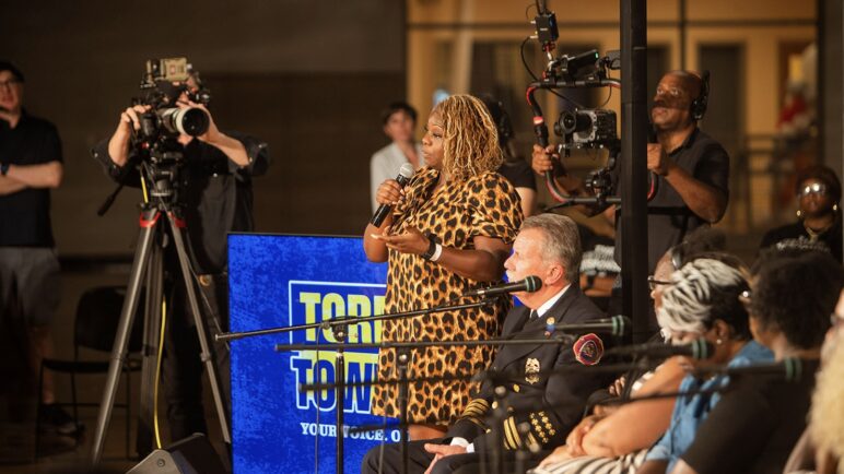 A person speaks in front of cameras at a Tornado Town Hall.