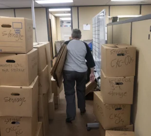 A volunteer walks between boxes in a KCUR storage room.