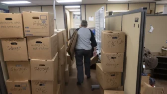 A volunteer walks between boxes in a KCUR storage room.