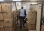 A volunteer walks between boxes in a KCUR storage room.