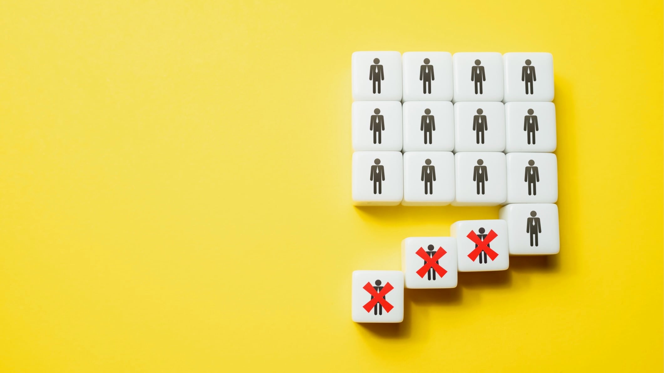 White cubes with stick-figure person icons are arranged in a grid on a bright yellow background. Several cubes have fallen away from the group, and three of them are marked with large red Xs, symbolizing layoffs or people being removed from a workforce
