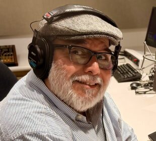Headshot of KVMR GM Luis Estrada, wearing a gray hat and headphones in a studio