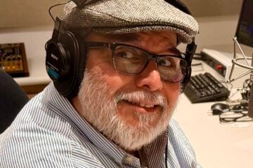 Headshot of KVMR GM Luis Estrada, wearing a gray hat and headphones in a studio