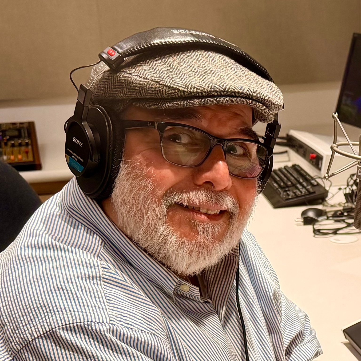 Headshot of KVMR GM Luis Estrada, wearing a gray hat and headphones in a studio