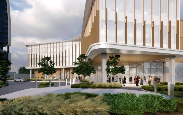 Rendering of KERA’s planned headquarters showing a modern, glass-fronted building with curved white overhangs and vertical wood accents. People gather outside a main entrance beneath a covered drop-off area, with landscaped grasses and trees lining the walkway.