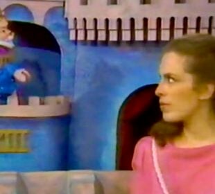 A scene from "Mister Rogers’ Neighborhood" shows Lady Aberlin in a pink top looking to the side, while King Friday XIII, a puppet wearing a crown, sits in a castle window.