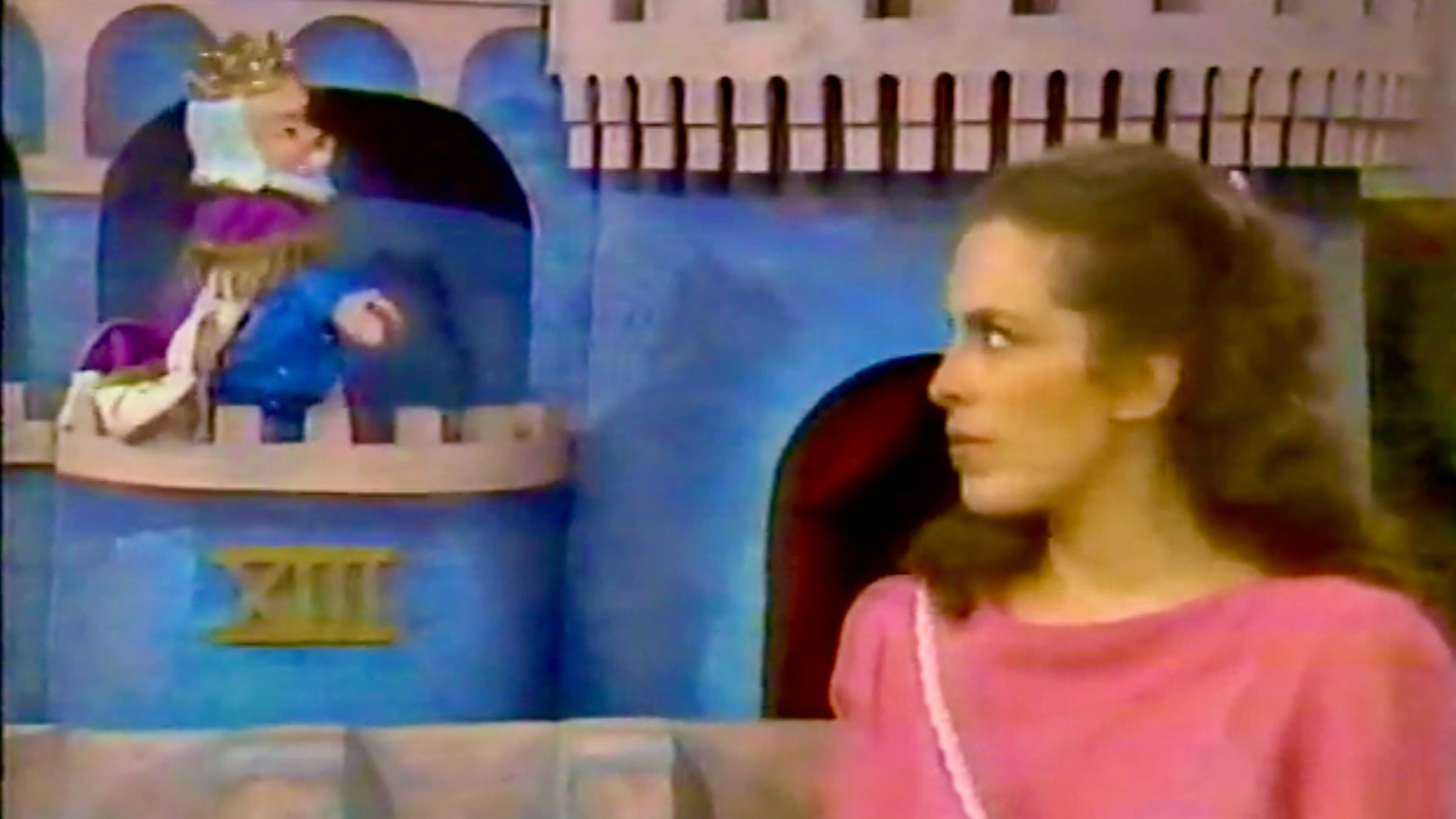 A scene from "Mister Rogers’ Neighborhood" shows Lady Aberlin in a pink top looking to the side, while King Friday XIII, a puppet wearing a crown, sits in a castle window.