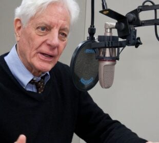 Former NPR President Kevin Klose speaking into a microphone in a radio studio.
