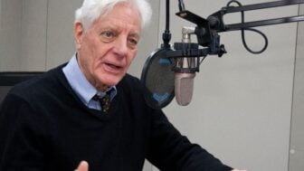 Former NPR President Kevin Klose speaking into a microphone in a radio studio.