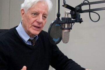 Former NPR President Kevin Klose speaking into a microphone in a radio studio.