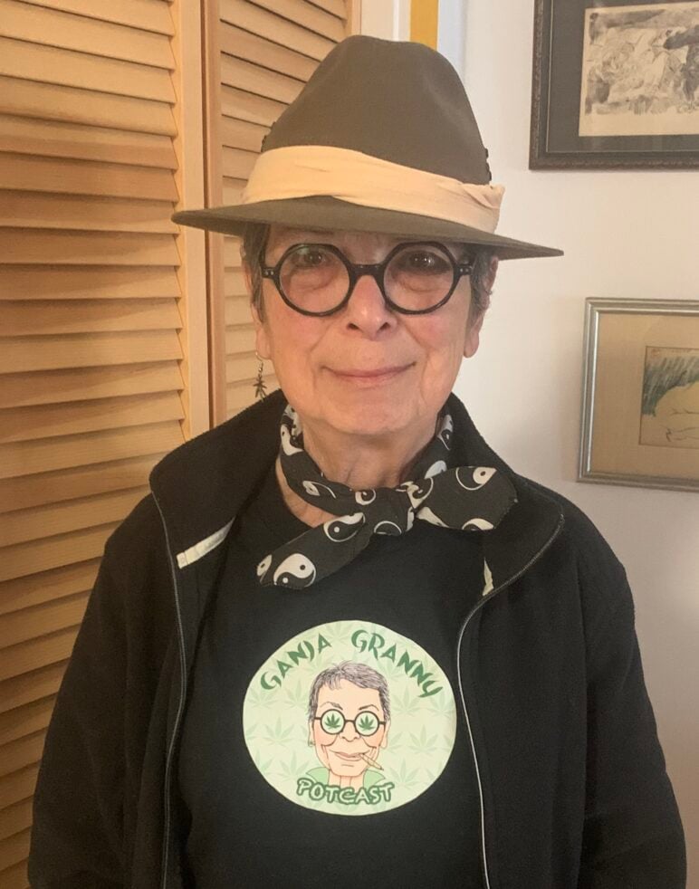 Podcast producer Karen Michel poses indoors wearing a hat and a Ganja Granny T-shirt featuring the podcast’s illustrated logo.