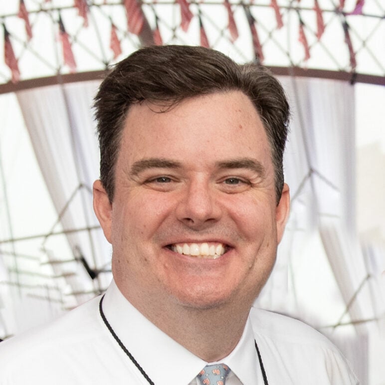 Headshot of "A Capitol Fourth" EP Michael Colbert smiling at the camera while wearing a white dress shirt and patterned tie.