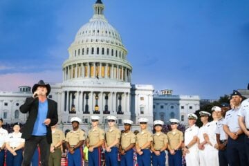 Trace Adkins performs onstage in front of the U.S. Capitol during the 2017 broadcast of "A Capitol Fourth," with members of the U.S. military standing behind him.