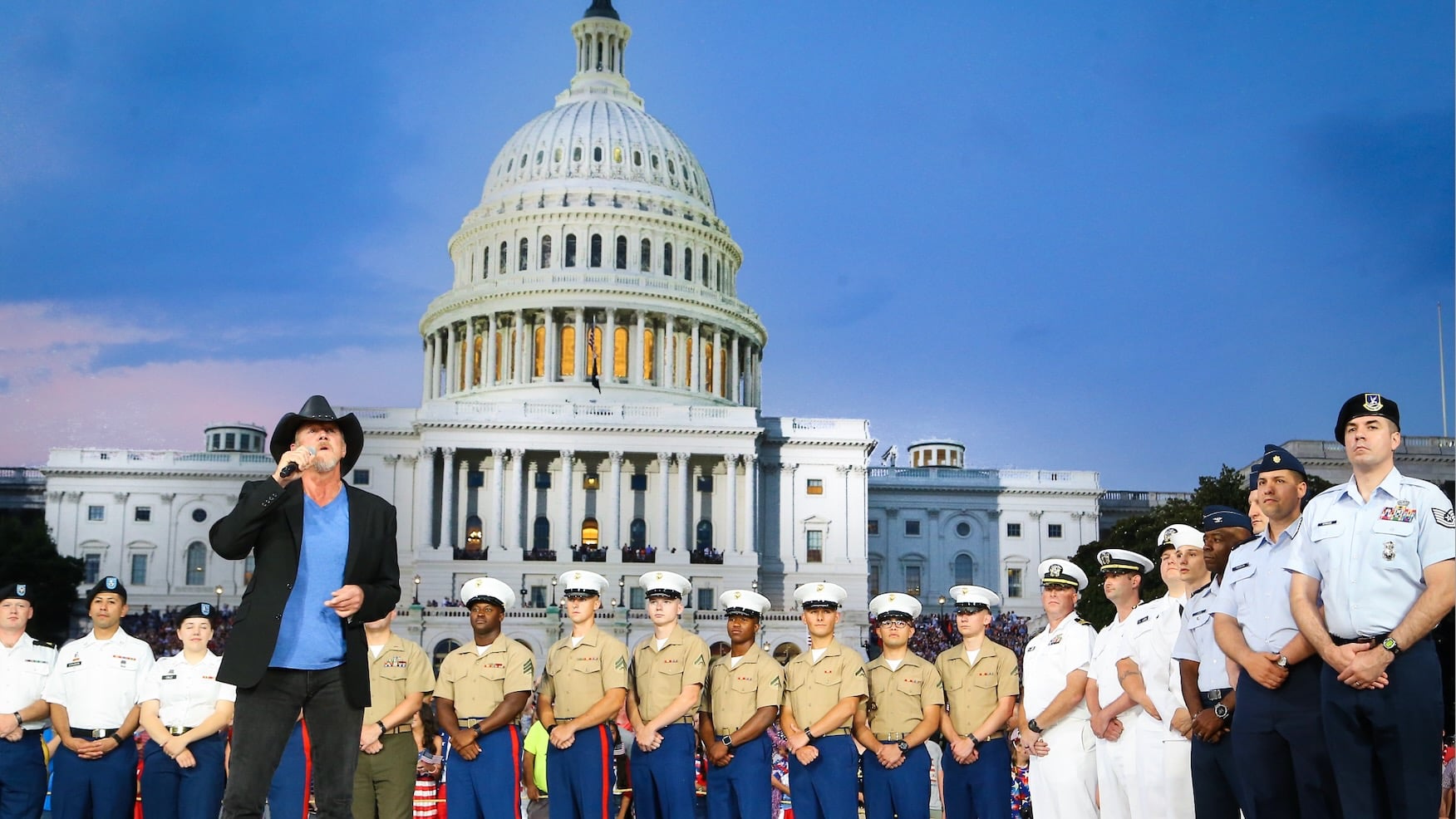Trace Adkins performs onstage in front of the U.S. Capitol during the 2017 broadcast of "A Capitol Fourth," with members of the U.S. military standing behind him.