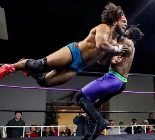 Tobias Storm launches horizontally into a flying tackle against "The Realist" Calvin Aldridge in a Show-Me State Wrestling match as spectators watch from ringside.