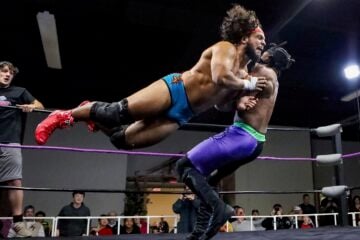 Tobias Storm launches horizontally into a flying tackle against "The Realist" Calvin Aldridge in a Show-Me State Wrestling match as spectators watch from ringside.
