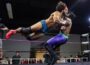 Tobias Storm launches horizontally into a flying tackle against "The Realist" Calvin Aldridge in a Show-Me State Wrestling match as spectators watch from ringside.