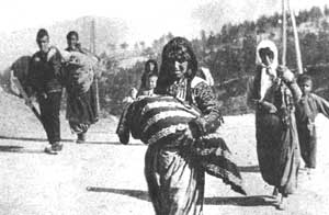 Woman carrying draped body with mountains in distance