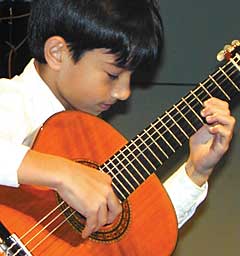 Boy bends over his guitar in performance