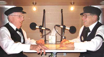 Two guys in black caps with matching microphones in StoryCorps booth